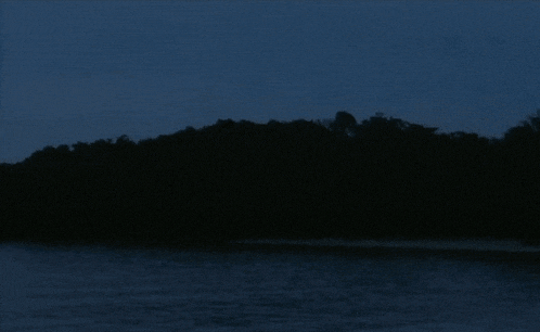 a dark lake with trees in the background and a blue sky