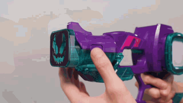 a person is holding a purple toy gun in their hand