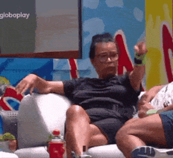 a woman with glasses is sitting on a couch with a globeplay logo in the background