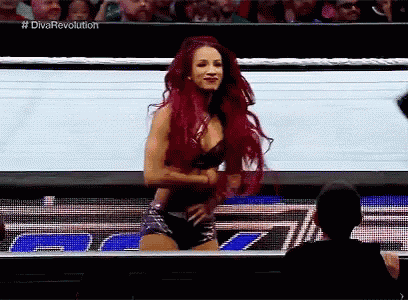 a woman with red hair is standing in front of a crowd while wearing shorts and a bra .