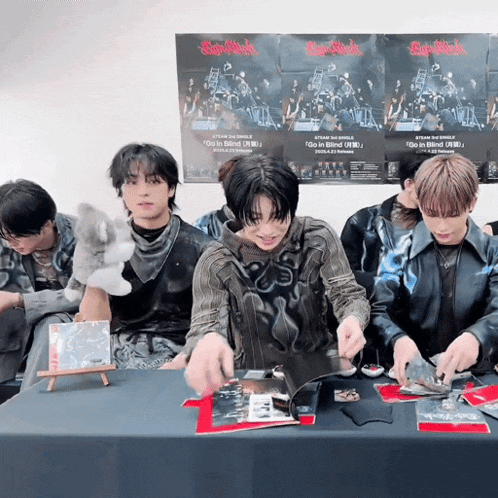 a group of young men are sitting around a table with posters on the wall behind them that say super rock