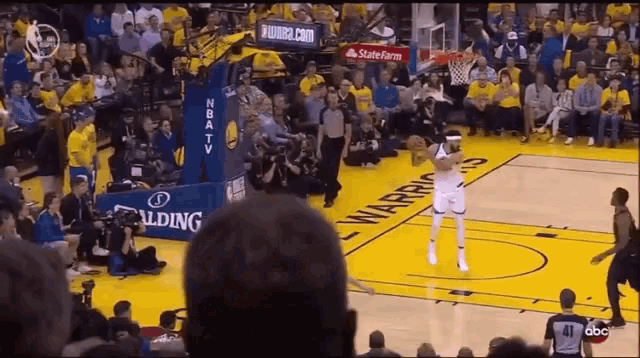a basketball game is being played in front of a crowd with a spalding banner in the background