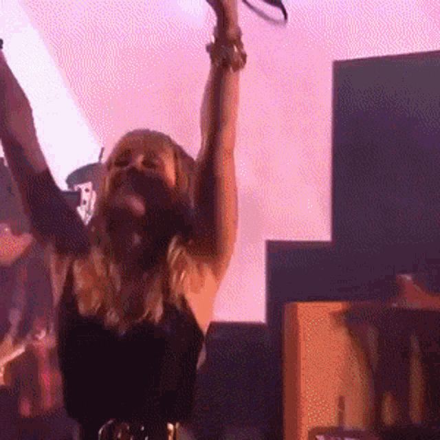 a woman is dancing with her arms in the air in a dark room