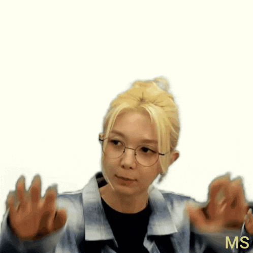 a woman wearing glasses and a plaid shirt waves her hands