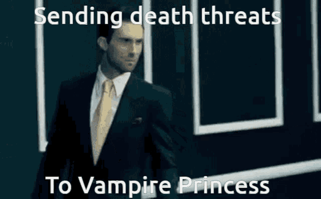 a man in a suit and tie is standing in front of a wall with the caption sending death threats to vampire princess .