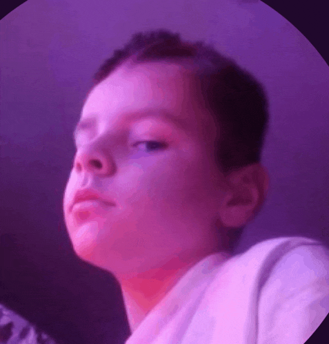 a young boy is making a funny face in a purple circle .