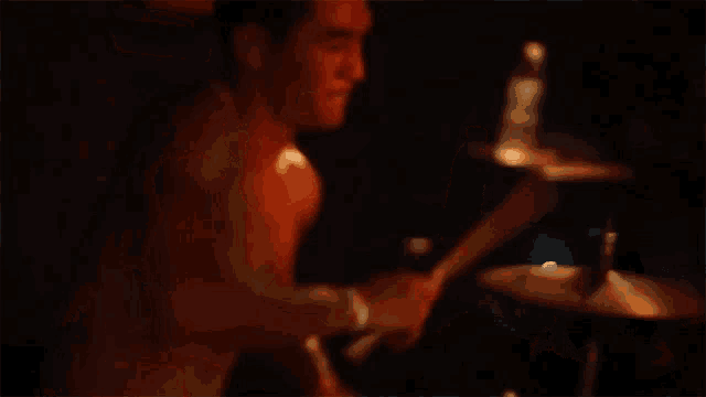 a man playing drums in a dark room with a bottle of water next to him