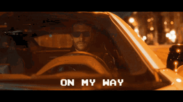 a man wearing sunglasses is driving a car with the words " on my way " above him