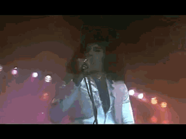 a man singing into a microphone on a stage with lights behind him