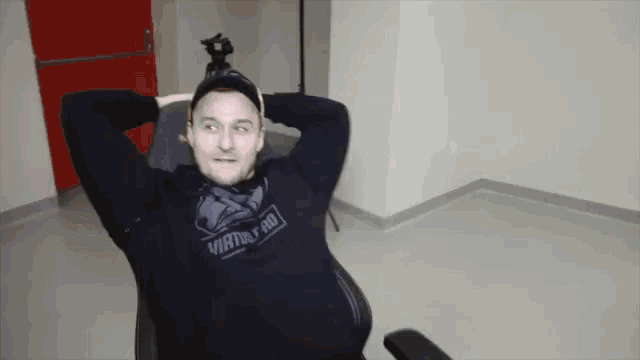 a man sitting in a chair with his hands behind his head wearing a sweatshirt that says virtue hd