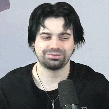 a man wearing a black shirt and a cross necklace is talking into a microphone ..