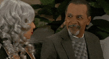a man in a suit and a woman in a wig are sitting next to each other