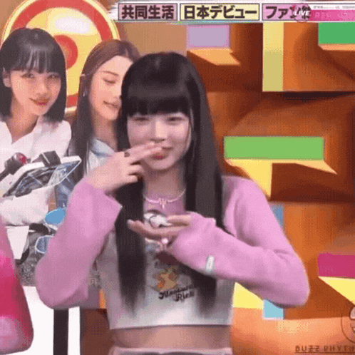 a girl in a pink sweater is holding a remote control in her hand .