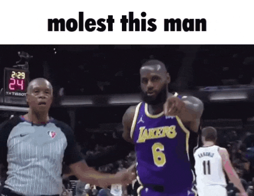 a basketball player in a lakers jersey is pointing at a referee .