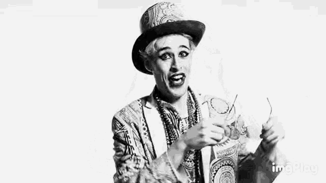 a black and white photo of a clown wearing a top hat and necklace .