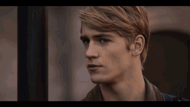 a close up of a young man 's face with blonde hair