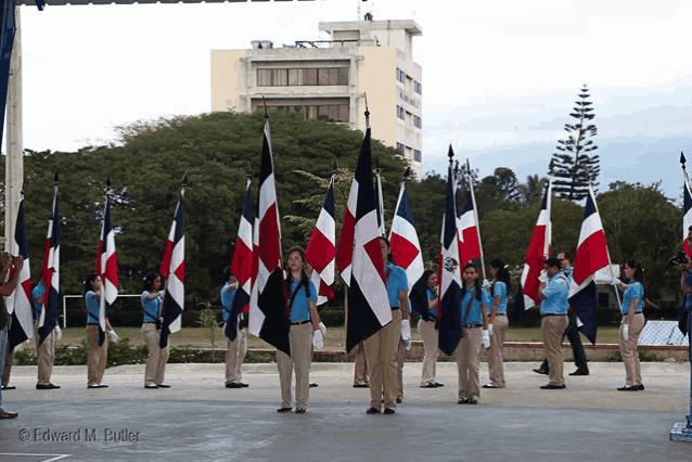 a group of people holding flags with edward m. butler written on the bottom right