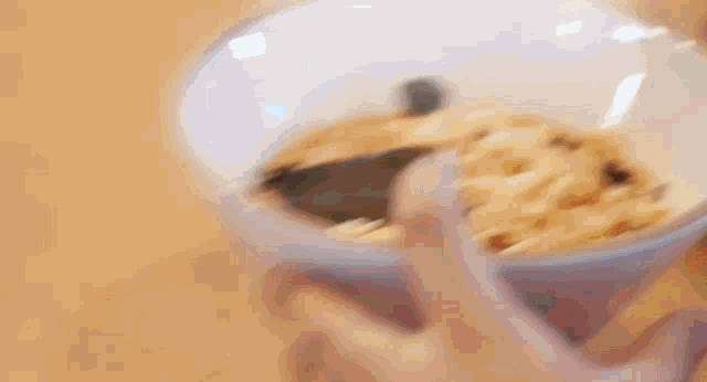 a person is holding a bowl of cereal with a spoon in it .