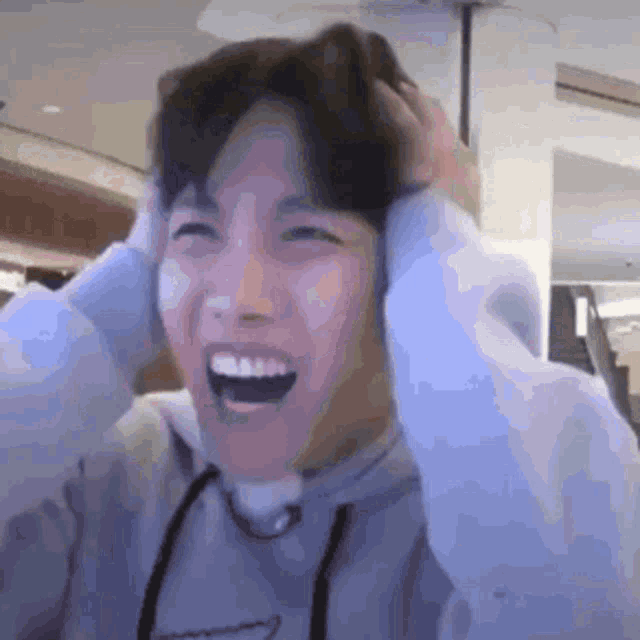 a man in a hoodie is laughing and holding his head .