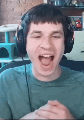 a man wearing headphones and a green shirt is laughing with his mouth open