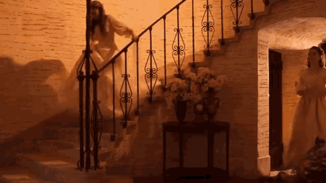 a woman walking down a set of stairs with a wrought iron railing