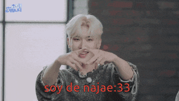 a man is making a heart shape with his hands and the words soy de najae : 33 are visible in red