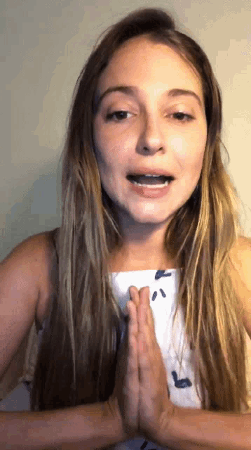 a woman with braces on her teeth holds her hands together in prayer