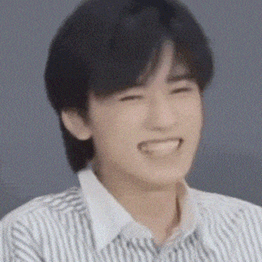 a young man in a striped shirt is smiling and looking at the camera .