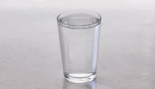 a glass of water with a ball in it on a counter .