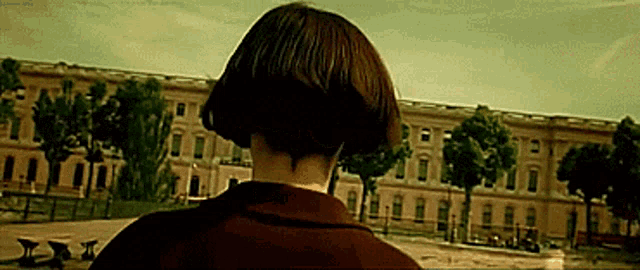 a woman with short hair stands in front of a building