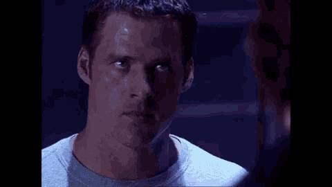 a man in a grey shirt is looking at a woman in a purple shirt