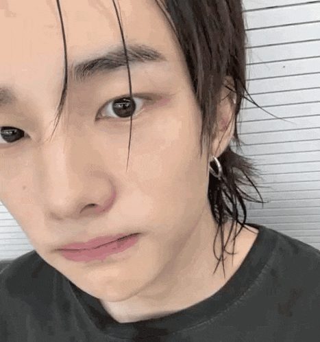 a close up of a person 's face with a ponytail and earrings .