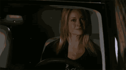 a woman is smiling while sitting in the driver 's seat of a car ..