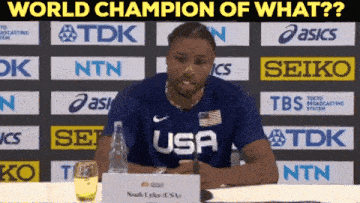 a man sitting at a table with a sign that says world champion of what on it