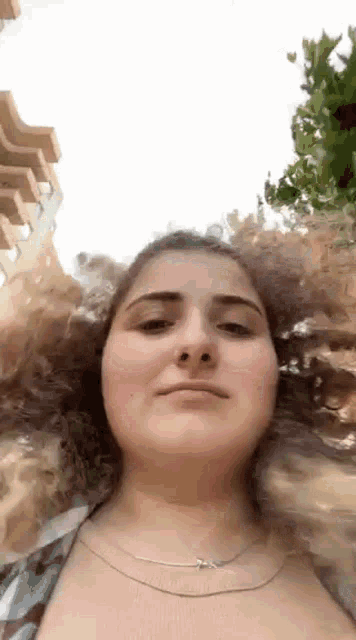 a woman with curly hair is making a funny face while looking at the camera .