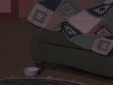 a person sitting on a couch under a blanket with a bowl of popcorn in front of them