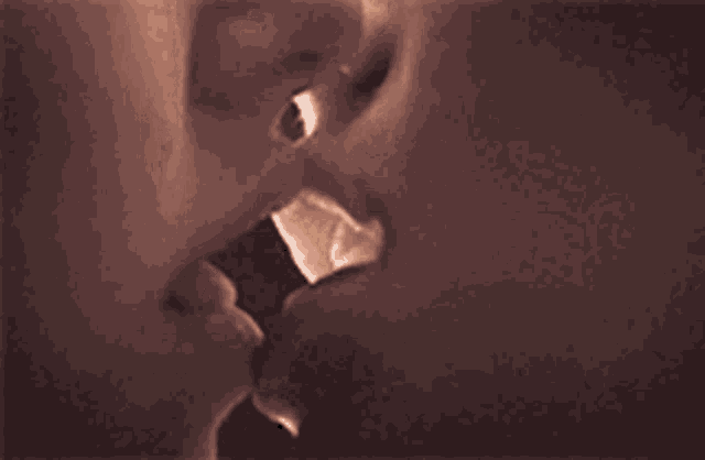 a close up of a woman 's lips kissing another woman 's .