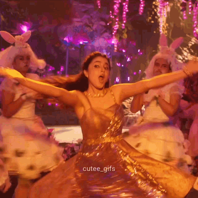 a woman in a gold dress is dancing with her arms outstretched and the caption cutee_gifs is below her