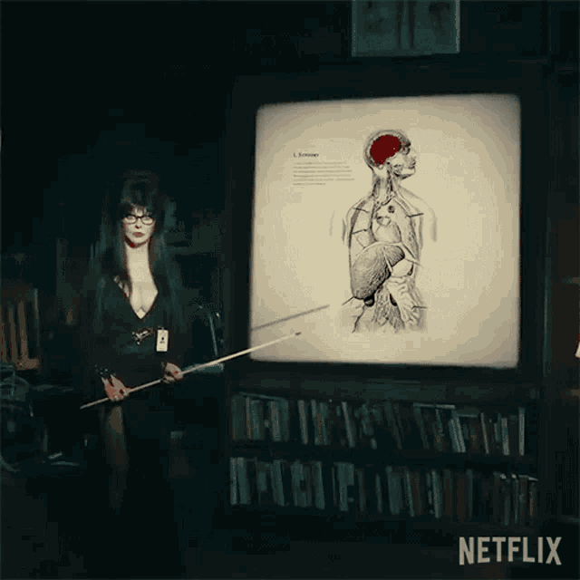 a woman is holding a pointer in front of a screen with a picture of a human body on it .