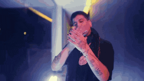 a man with a lot of tattoos on his arms is blowing a kiss