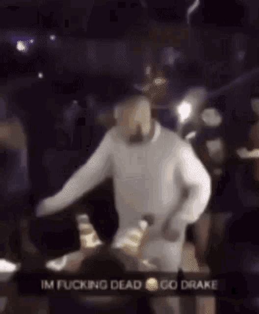 a man in a white sweater is dancing in front of a crowd at a concert .