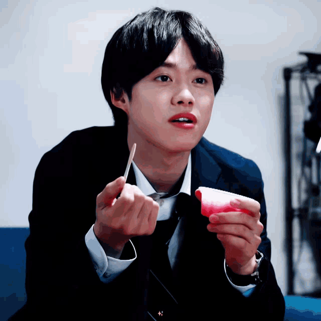 a man in a suit and tie is holding a pink object in his hands