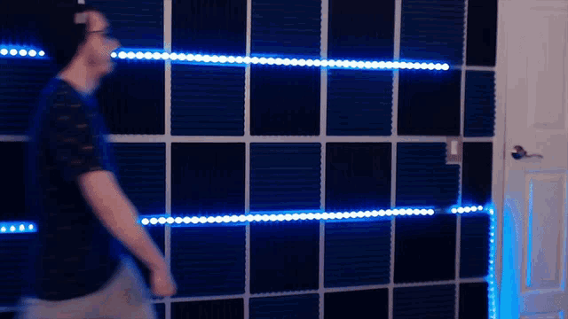 a man is standing in front of a wall with blue lights