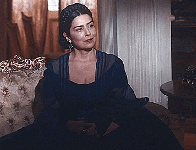 a woman in a blue dress is sitting on a couch in a room