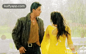 a man and a woman are standing in the rain holding hands .