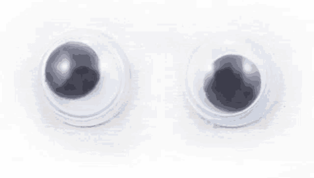 a pair of plastic googly eyes on a white background .