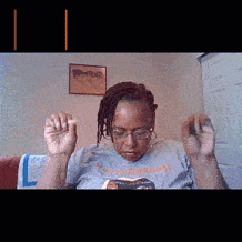 a woman wearing glasses and a t-shirt that says stemminds is sitting on a couch reading a book