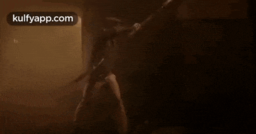 a man is standing in a dark room holding a spear in his hand .