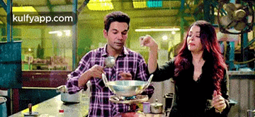 a man and a woman are standing in a kitchen cooking food .