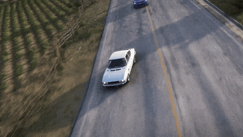 a white car is driving down a road with a yellow line